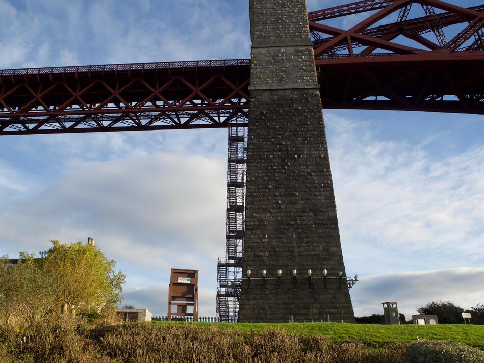 A side-on view of one of the pillars and the red bridge, with some stairs going up the side of the pillar.